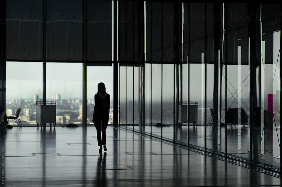 Silhouette of woman in big space with big windows and city view