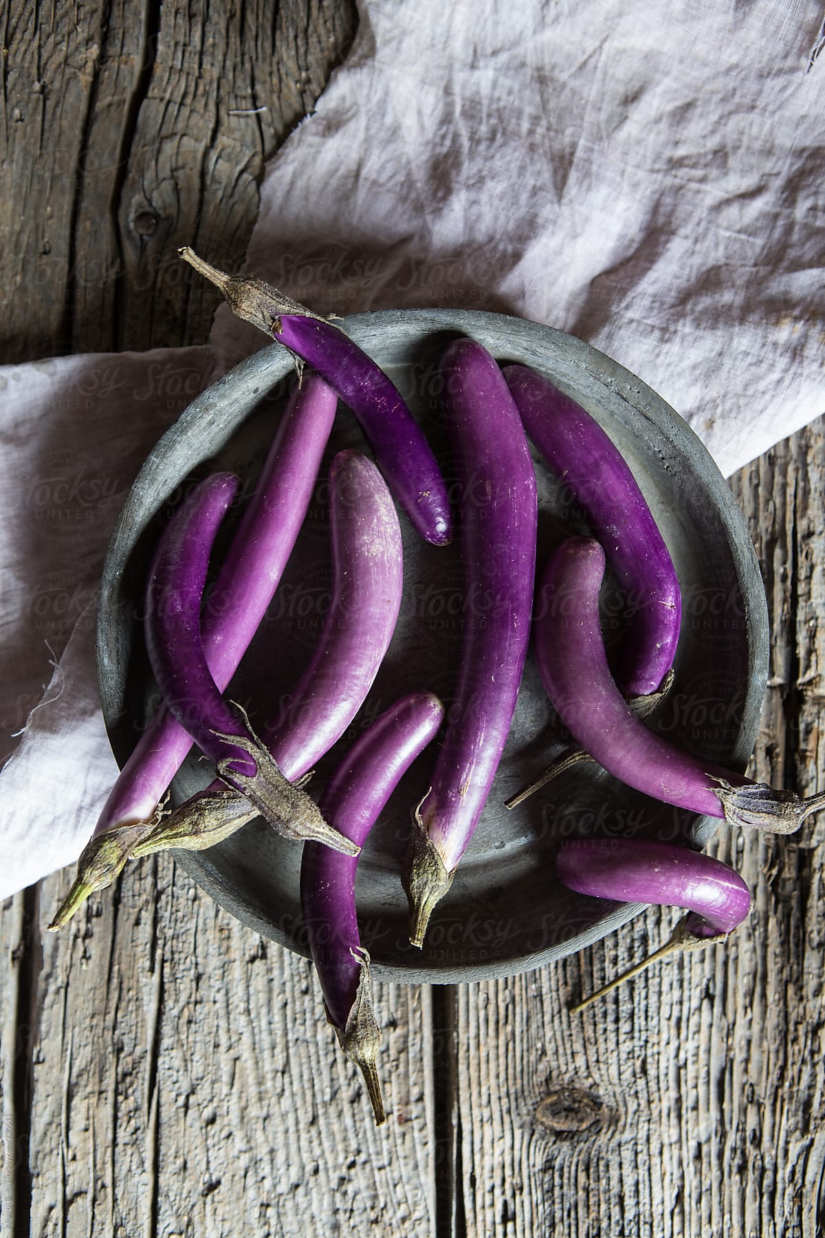 Fresh purple eggplants inside tray on wooden table