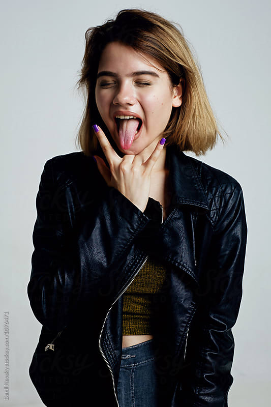 Teen girl with sign of horns sticking out tongue