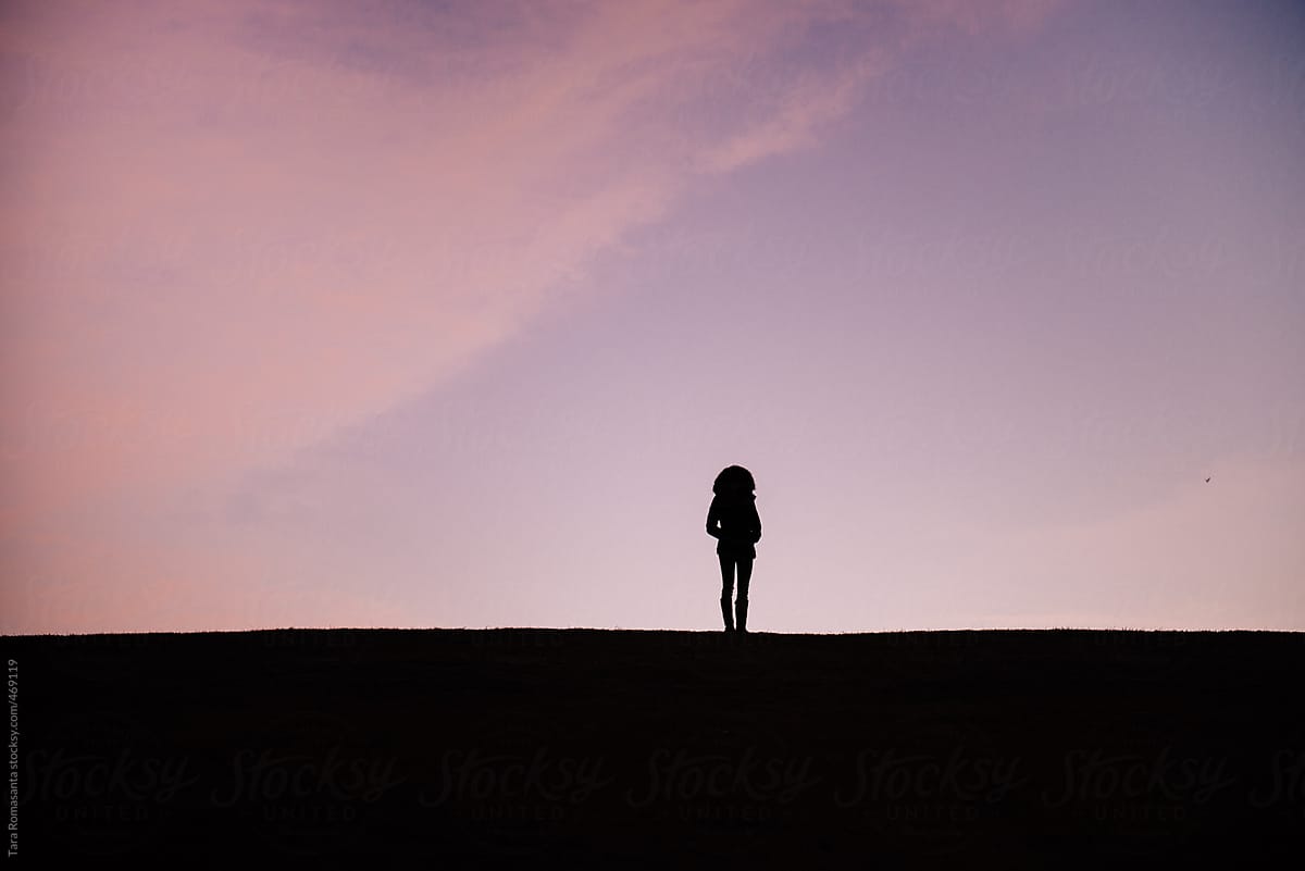 silhouette of a solitary woman gazing at a bird in the distance