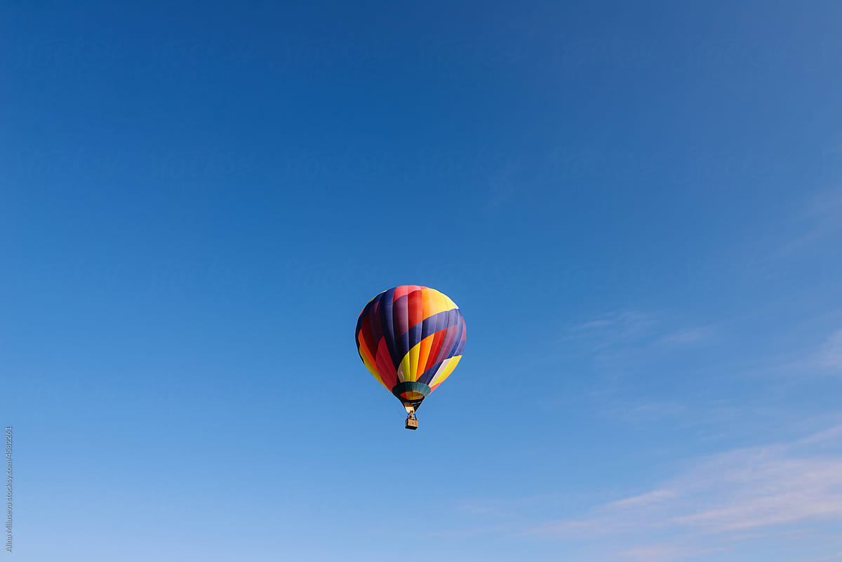 Multicolored hot air balloon in center of blue sky