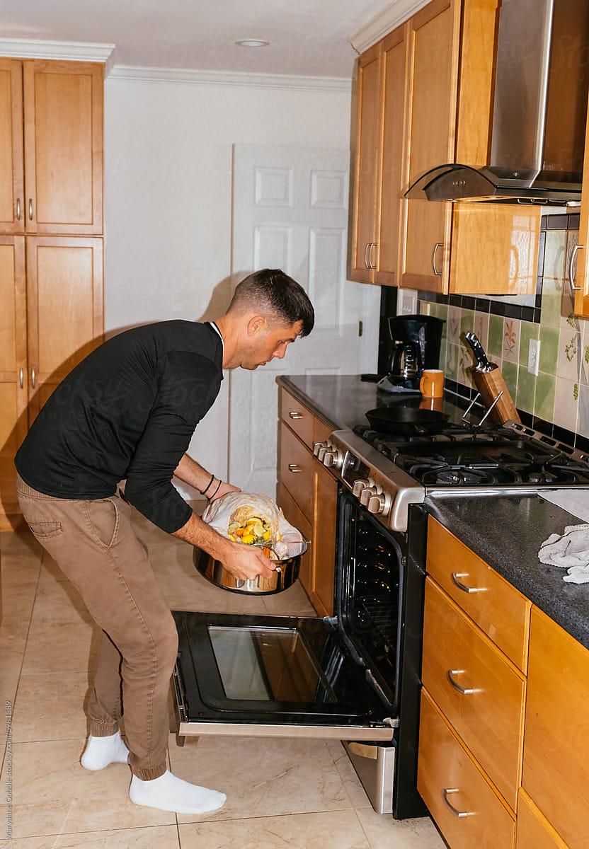 Man Putting Holiday Turkey in Oven