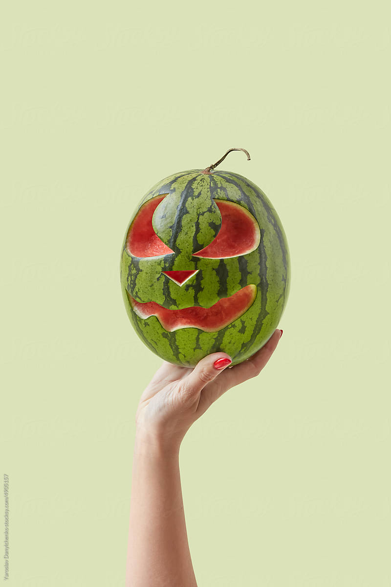 Halloween watermelon held by woman\'s hand.