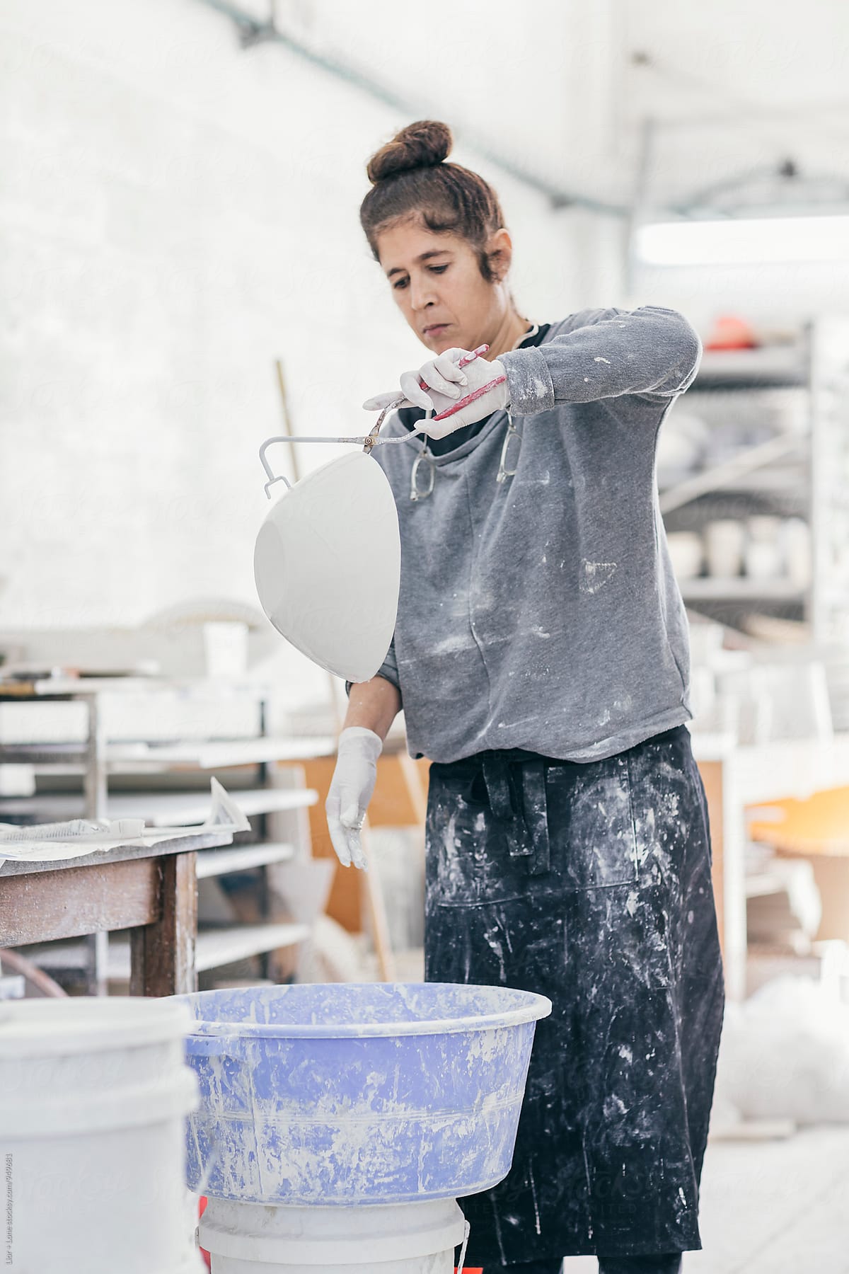 Female ceramic artist glazing a bowl in her studio
