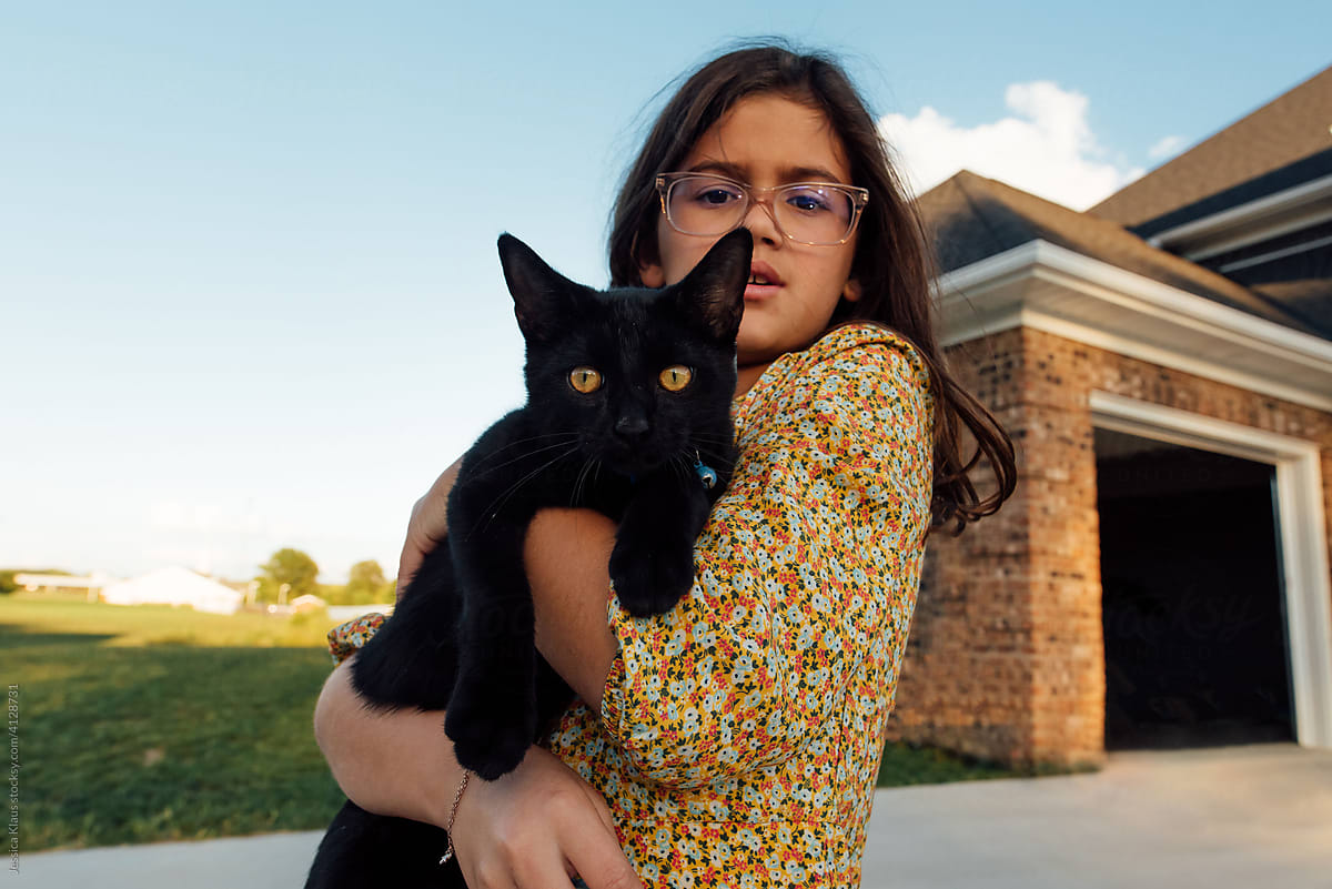 Black cat being held by girl.