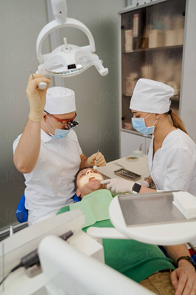 dentist and assistant doctor look at the client\'s teeth