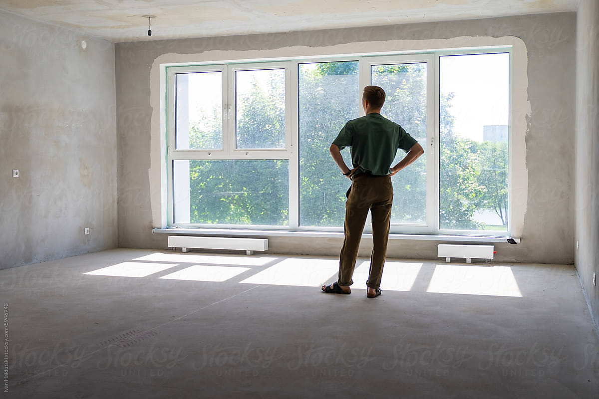 millennial man in front of big window in a new home apartment