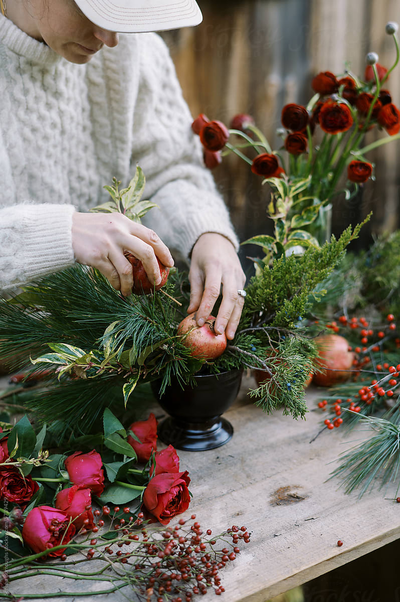 florist in white knit sweater making christmas floral centerpiece