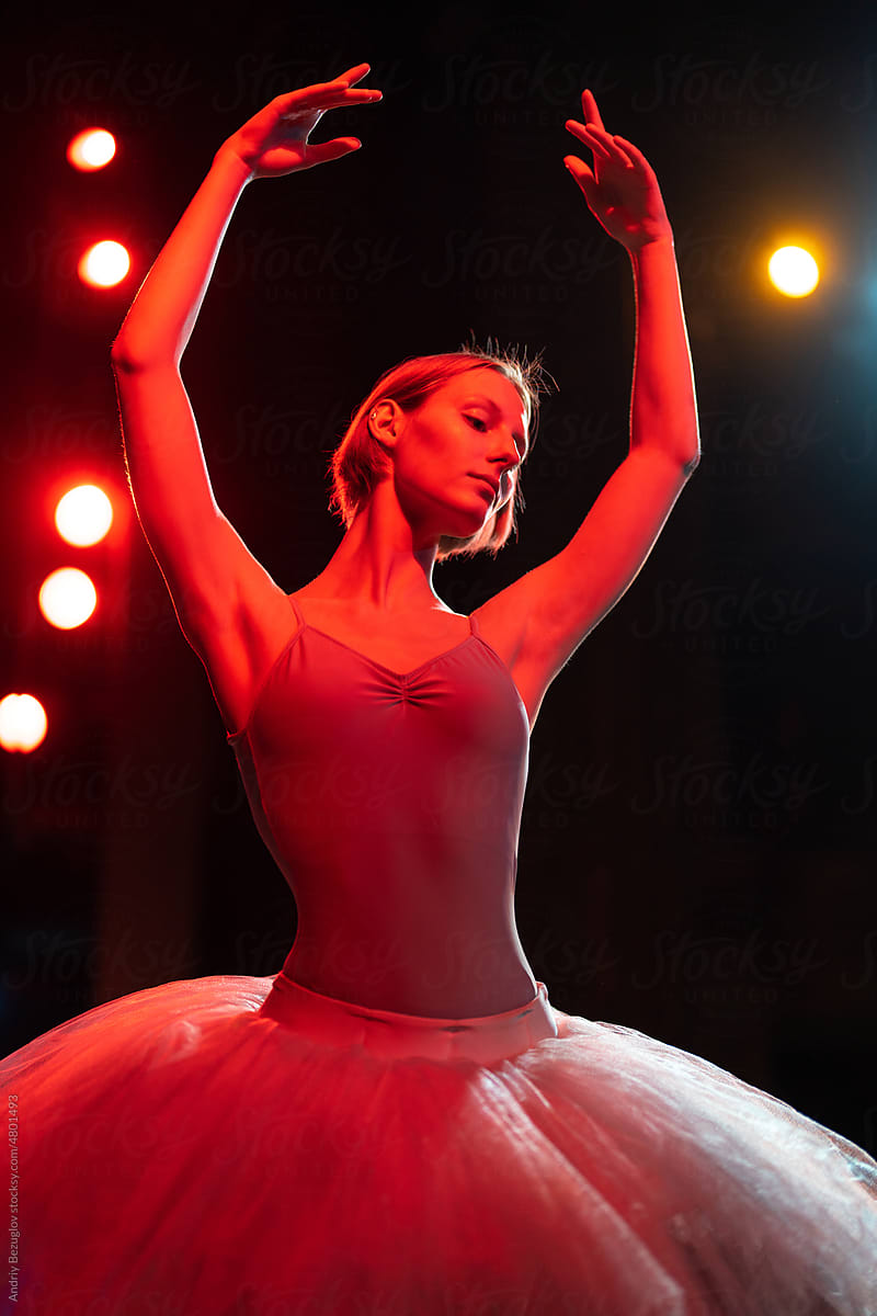 Caucasian brunette ballerina girl performing dance around neon light