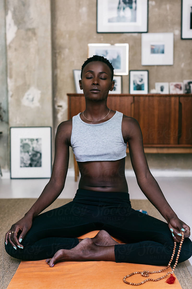 Slim Black Woman Meditating At Home By Stocksy Contributor