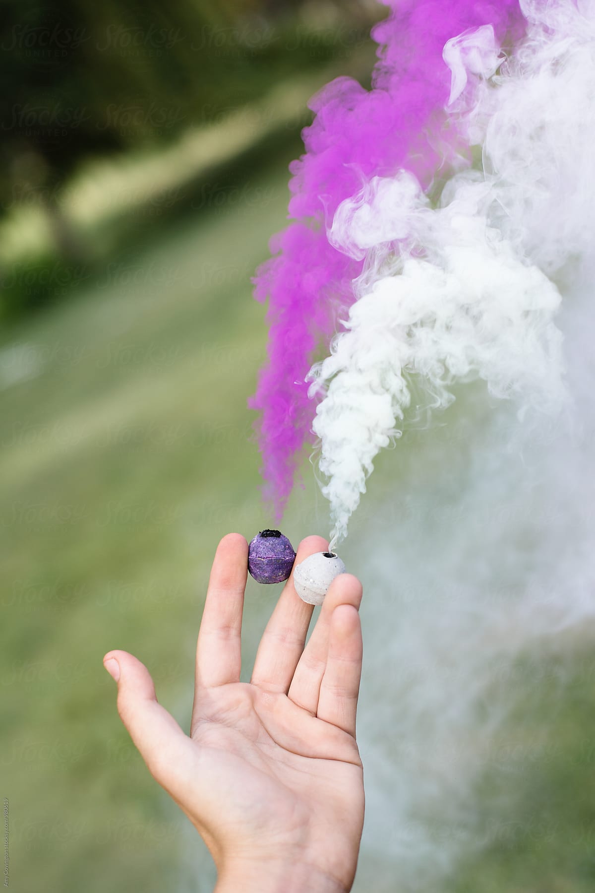 Hand Holding A Pair Of Smoke Bombs by Stocksy Contributor Amy Covington  - Stocksy