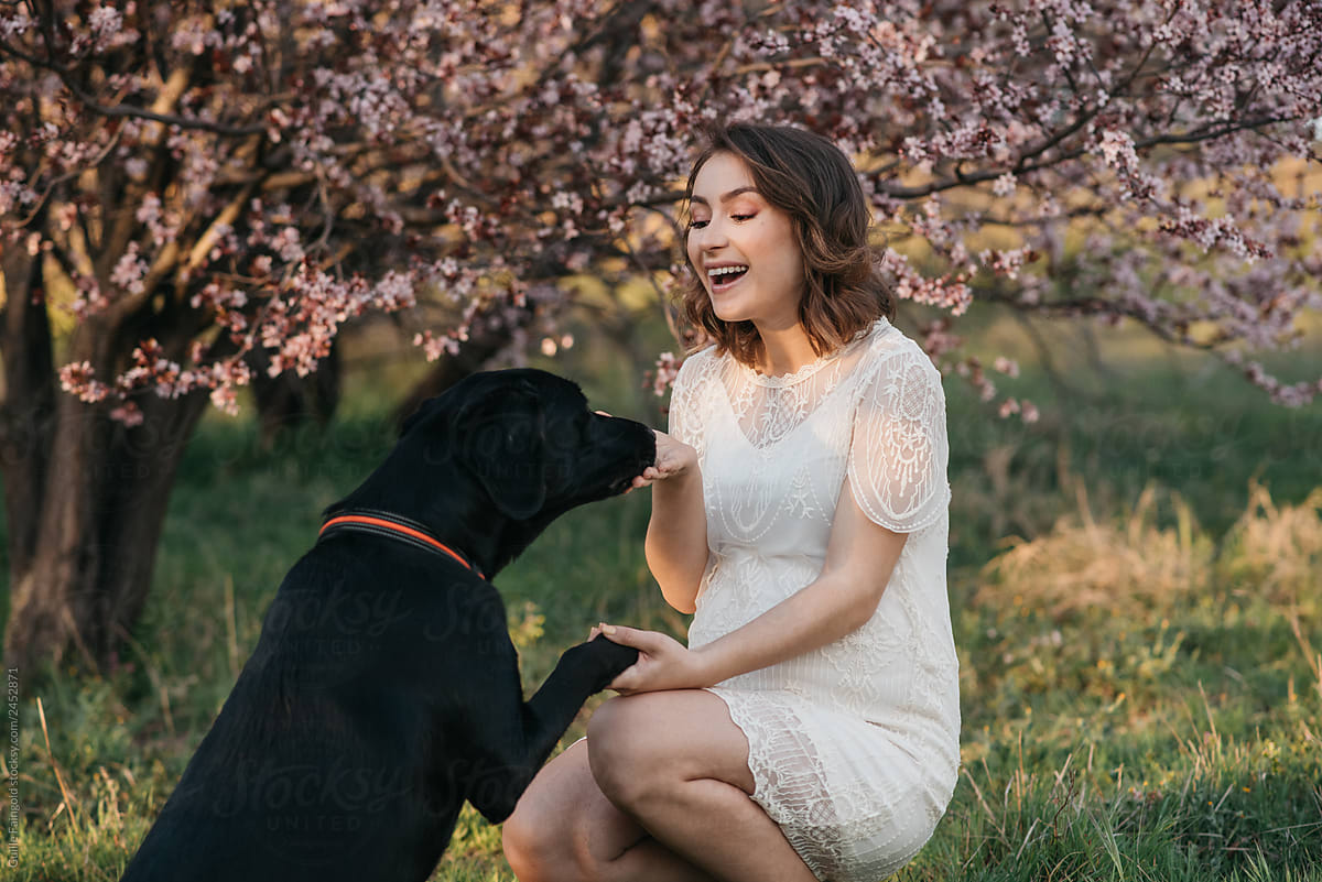Smiling pregnant woman with playful dog in nature
