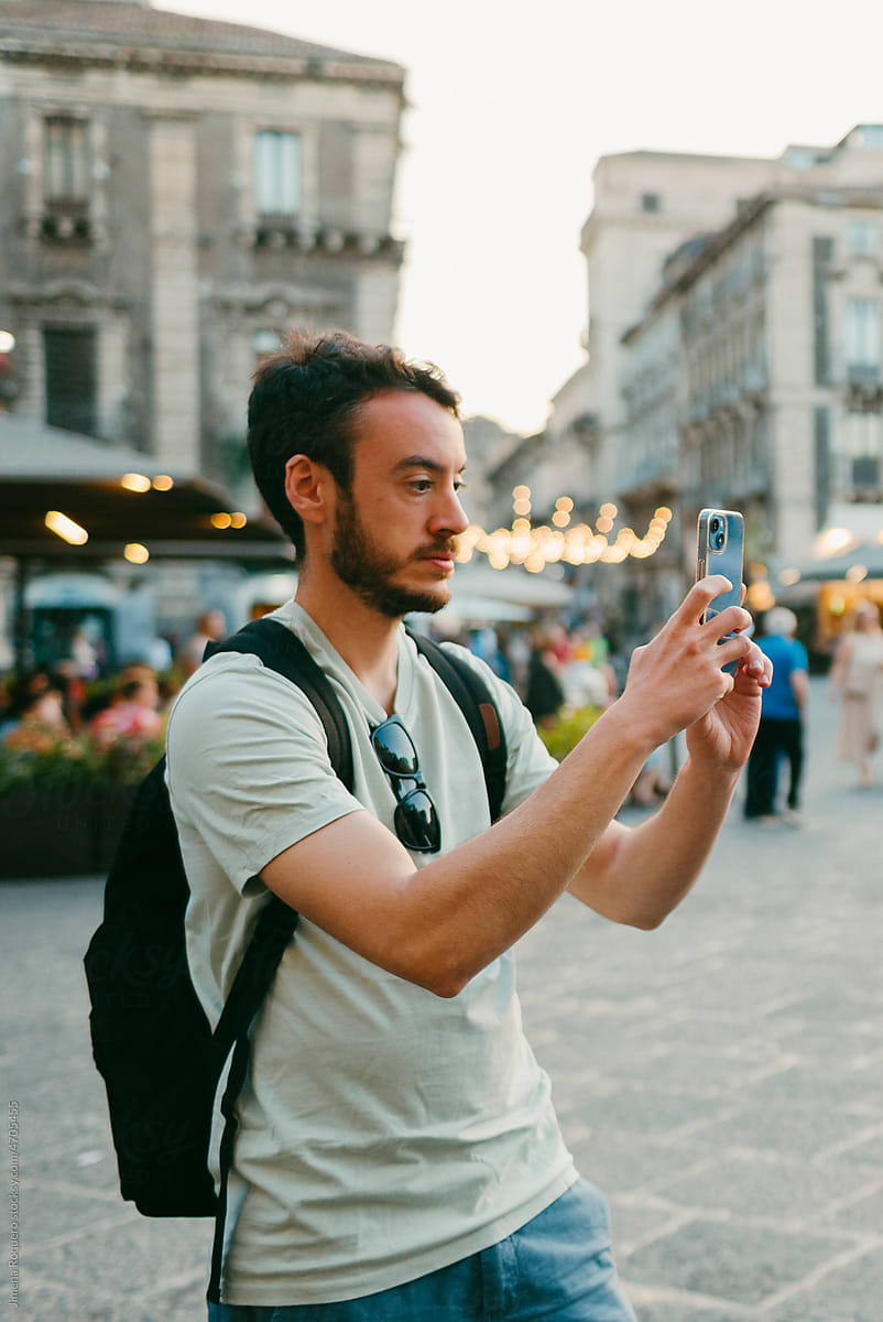 Tourist taking a photo on his smartphone in Italian city in warm day