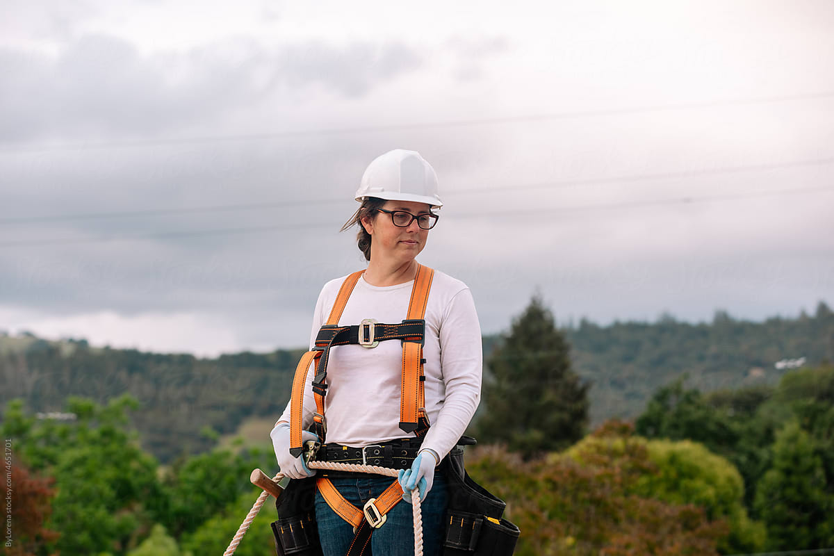 Woman  in construction holding harness at roof