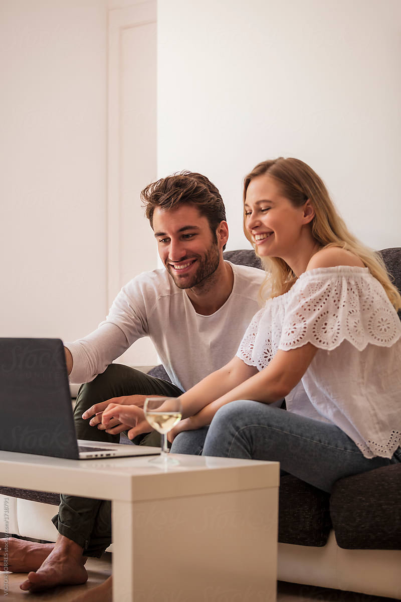 Cheerful couple watching laptop at home