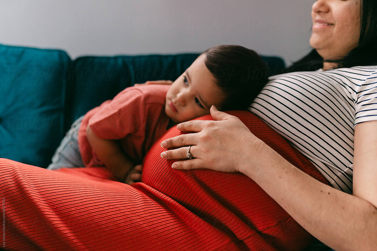 pregnant  mother cuddling toddler on the couch