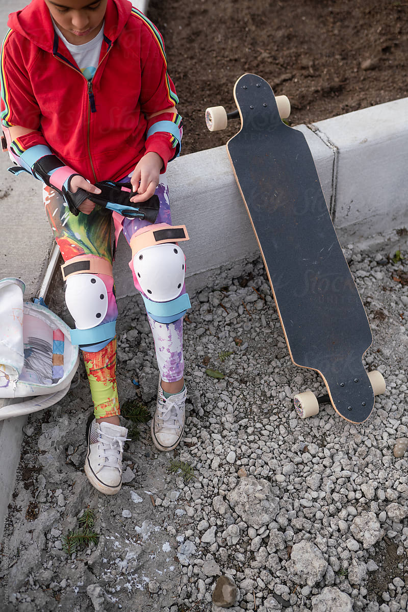 Girl puts on wrist pads to skateboard