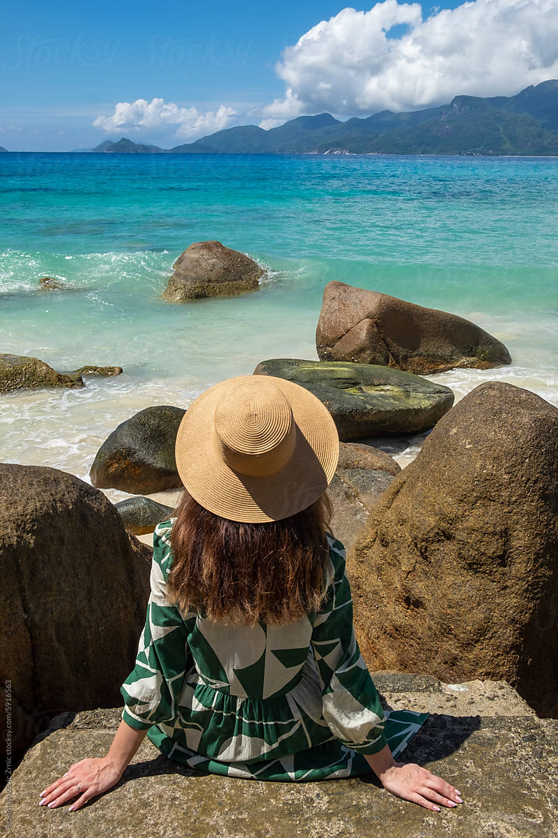 A female sitting on a rock on the beach in Seychelles