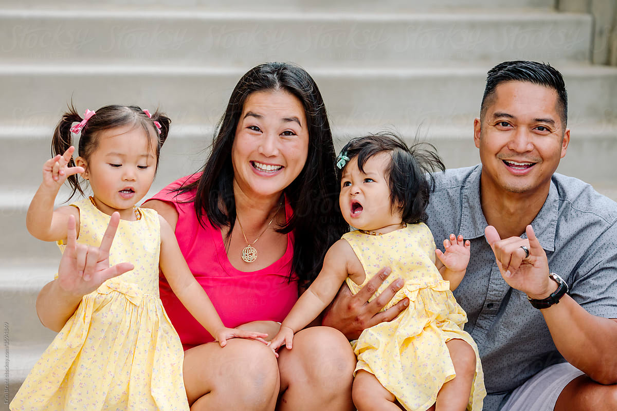 Young asian family on steps practices sign language