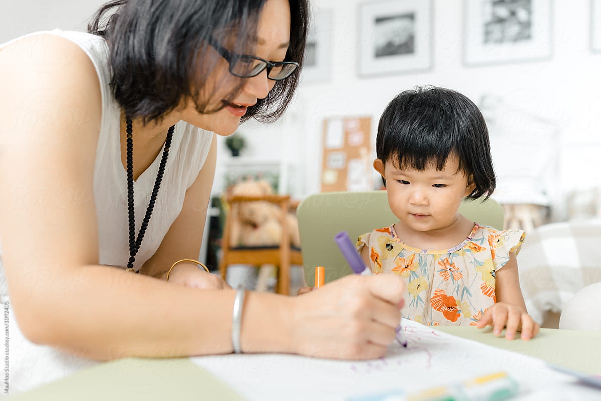 Little girl drawing pictures with her mother