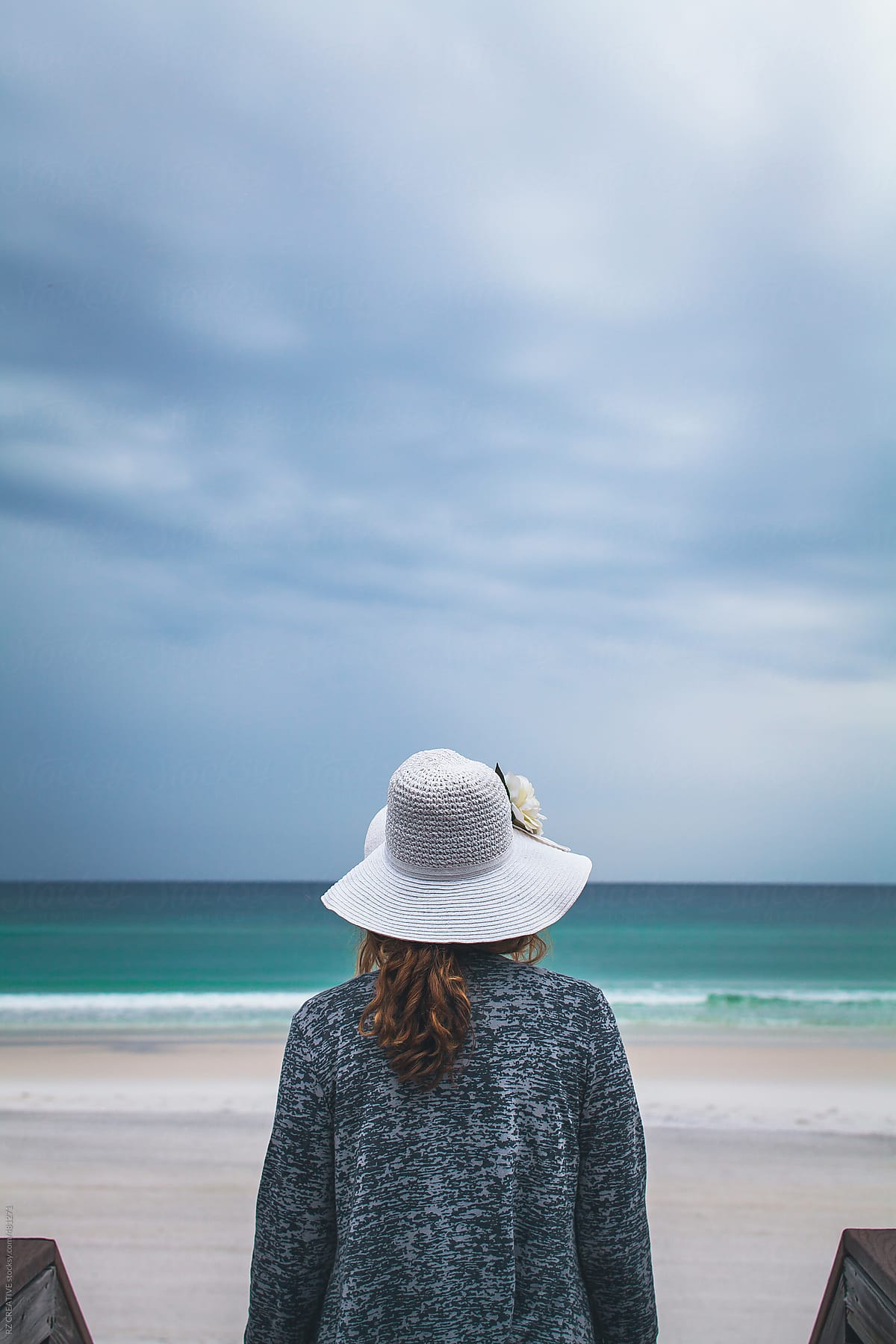 Woman with hat at dark beach.