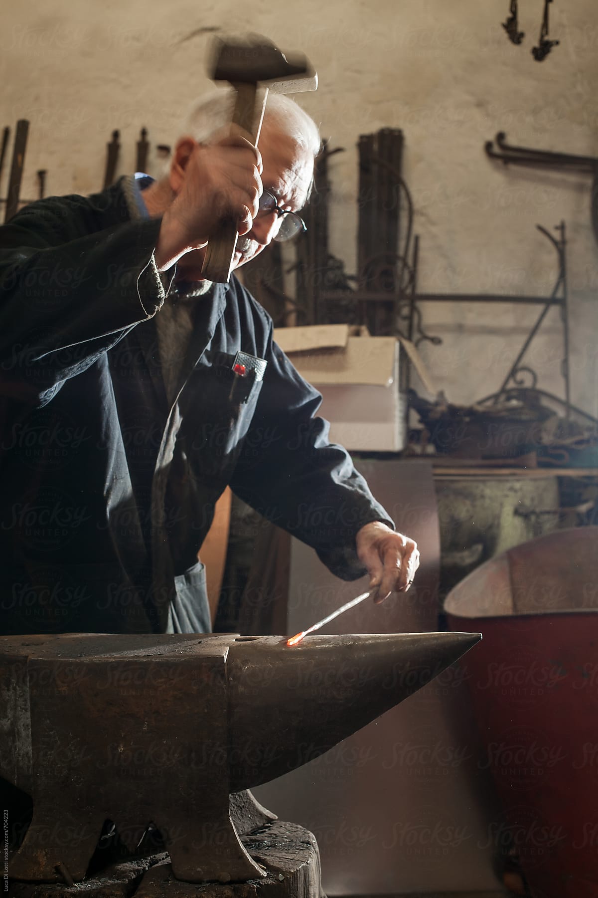 elder blacksmith hammering a red-hot iron rod