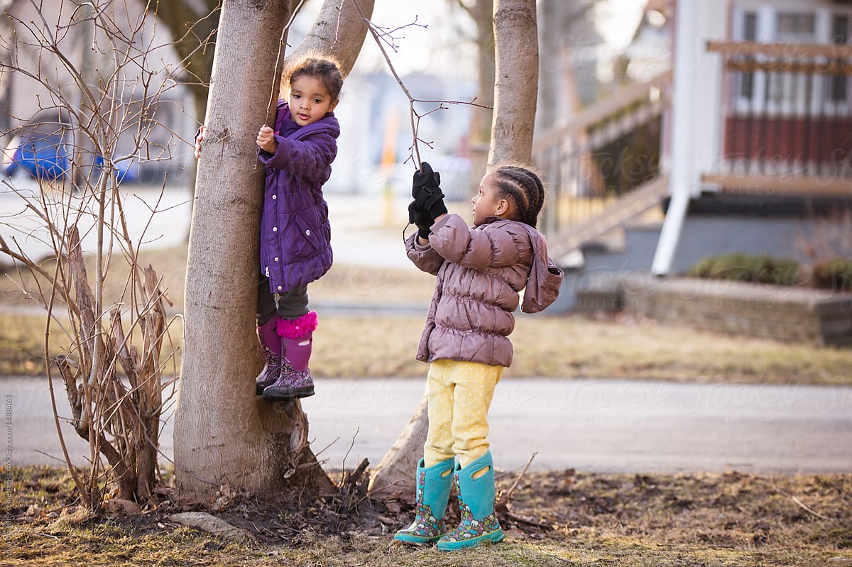 "Two children playing outside next to a tree" by Stocksy Contributor "anya brewley schultheiss"