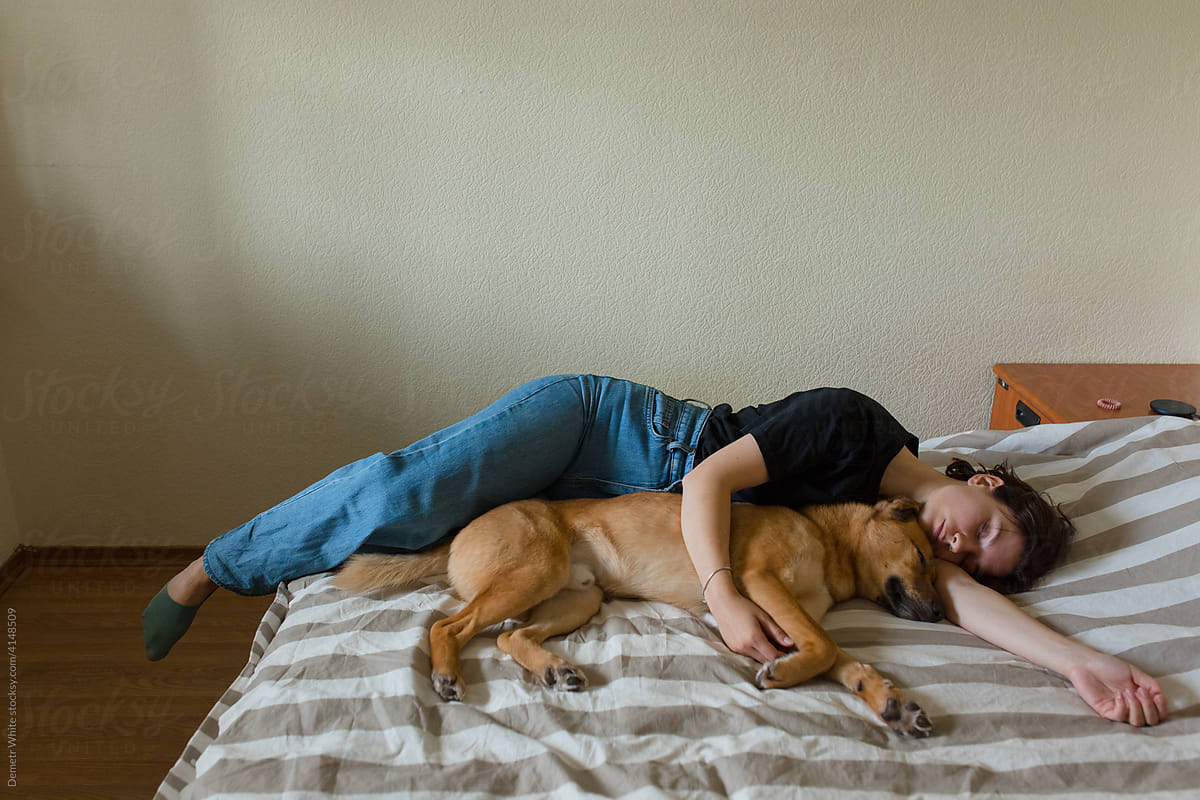 girl sleeping with a dog on the bed