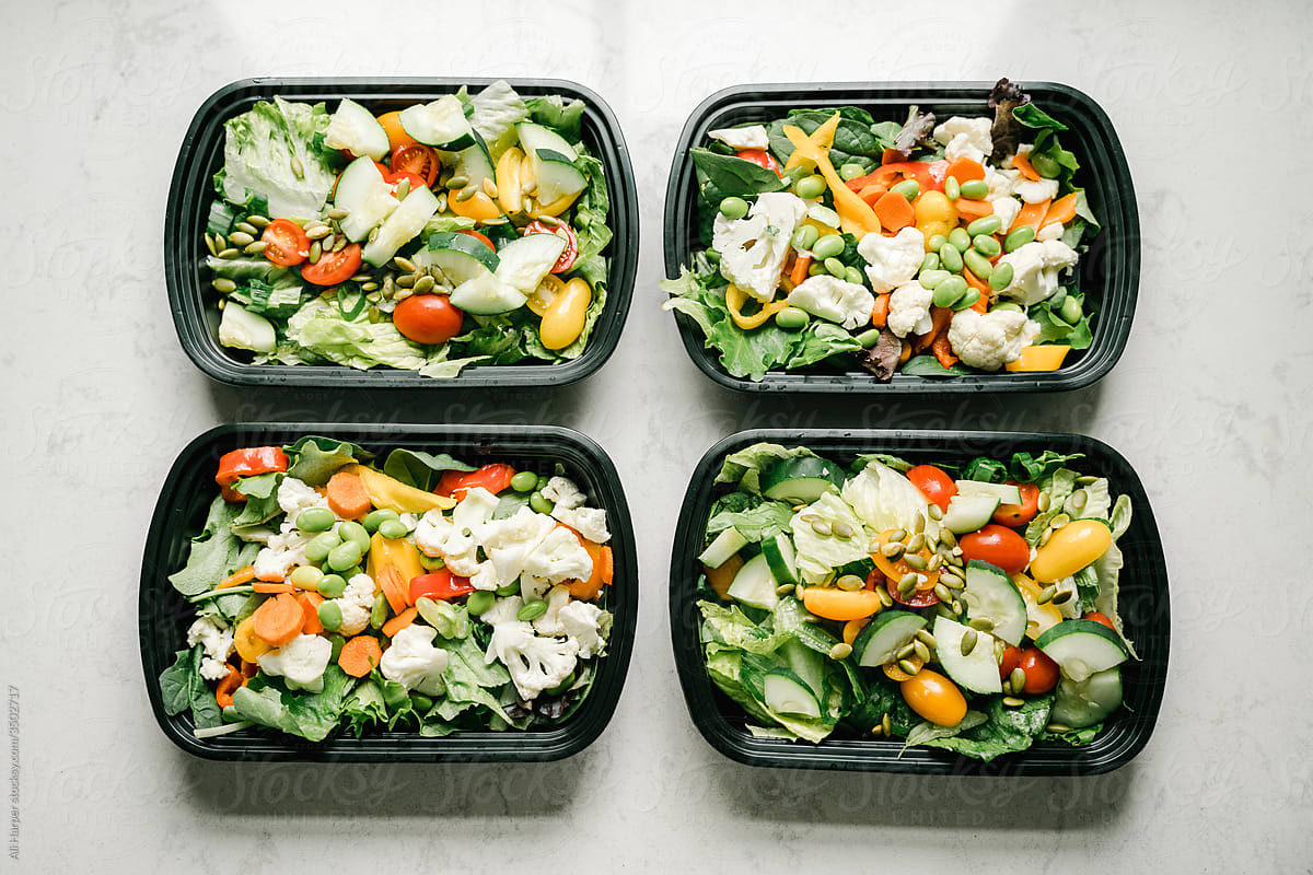 Four salad containers prepped for healthy meal planning