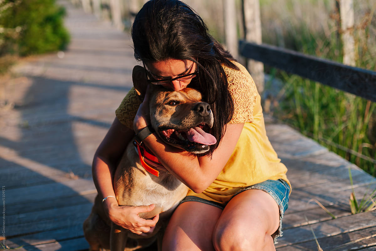 Woman in summer outfit hugging dog