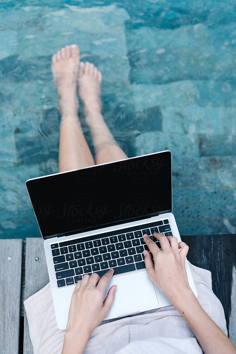 Woman using laptop at poolside