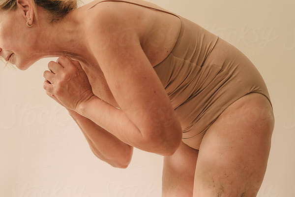 Cropped Crouching Elder Woman With Neutral Lingerie by Stocksy