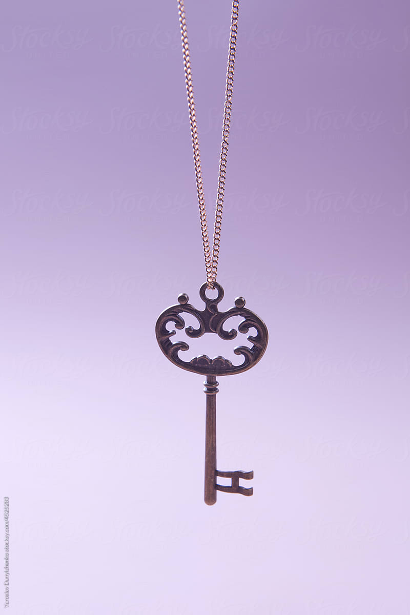 Bronze ornate key hanging on golden chain