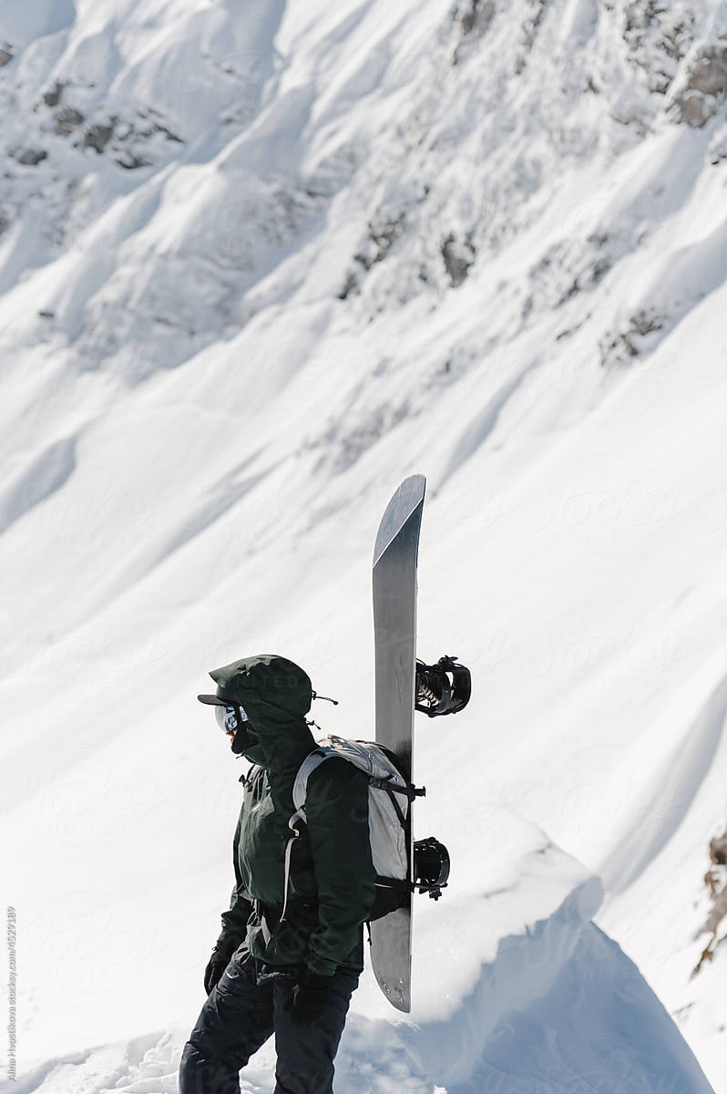 Male snowboarder walking up slope