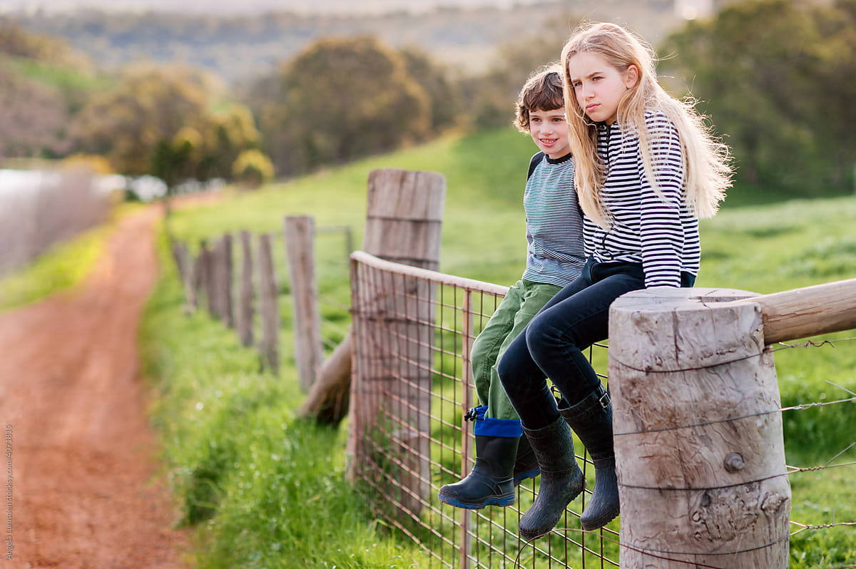 Kids sitting on farm gate