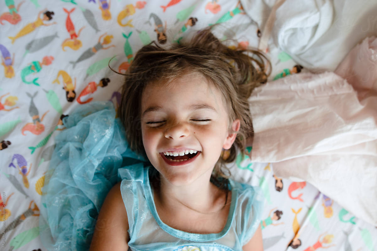 Overhead View Of Little Girl Laughing In Her Room by Stocksy