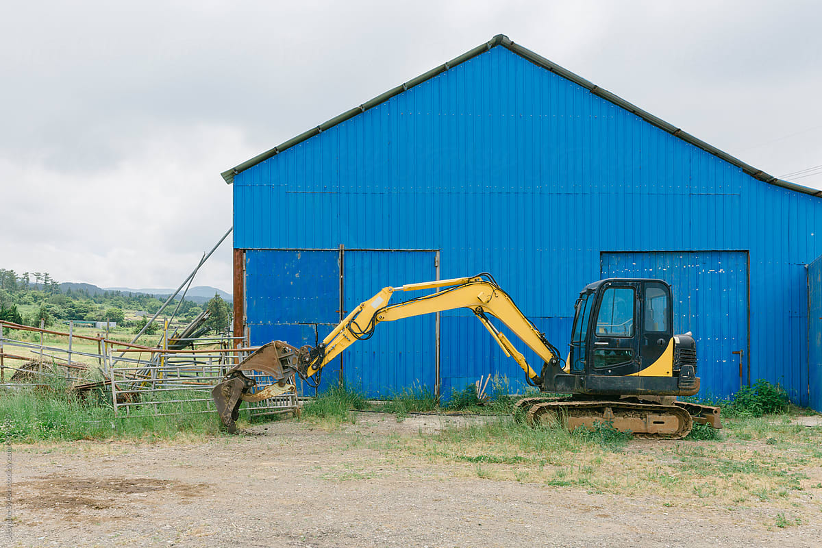Blue warehouse and yellow excavator