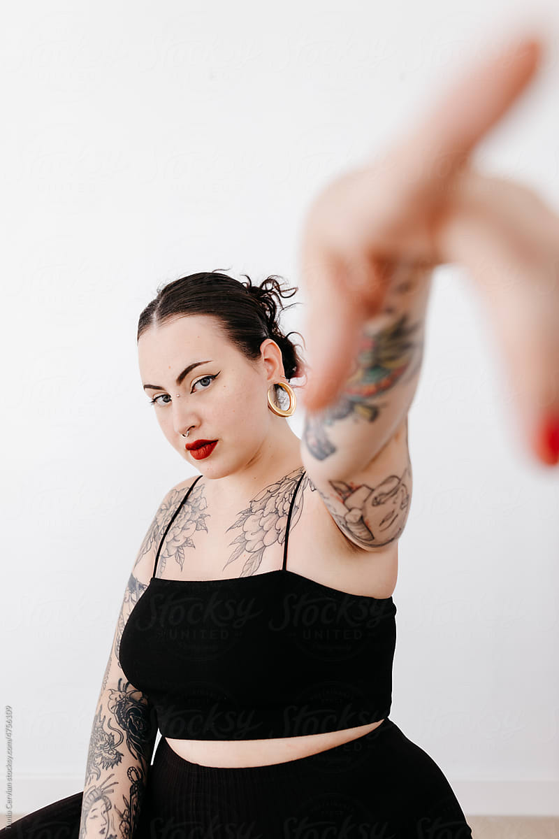 Tattooed woman pointing away in studio