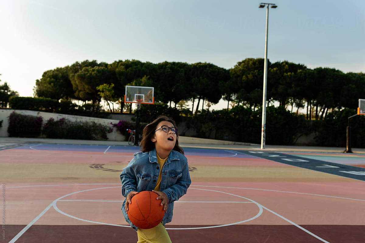Kid playing basketball after school at sports area