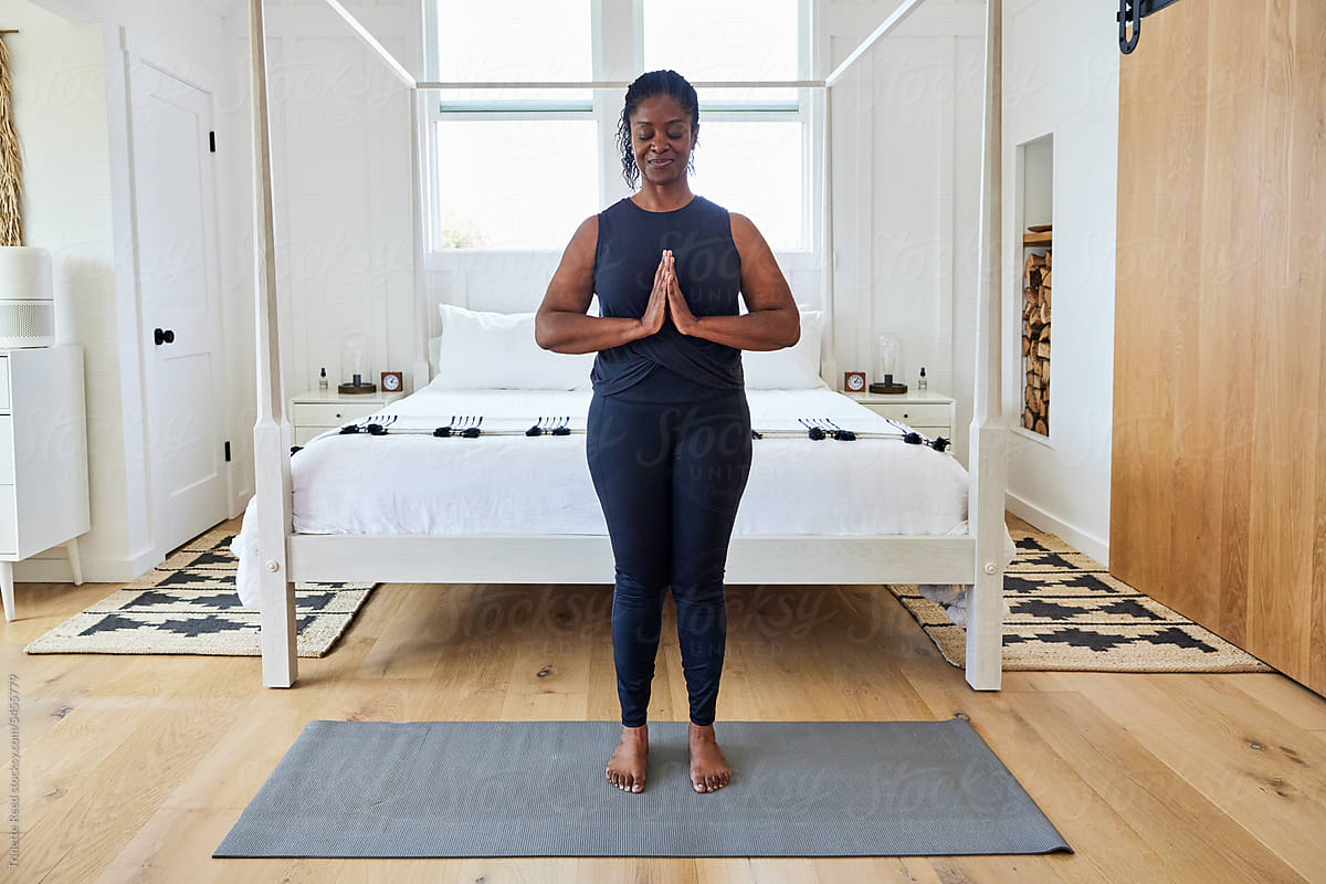 Mature Black woman doing yoga at home in bedroom