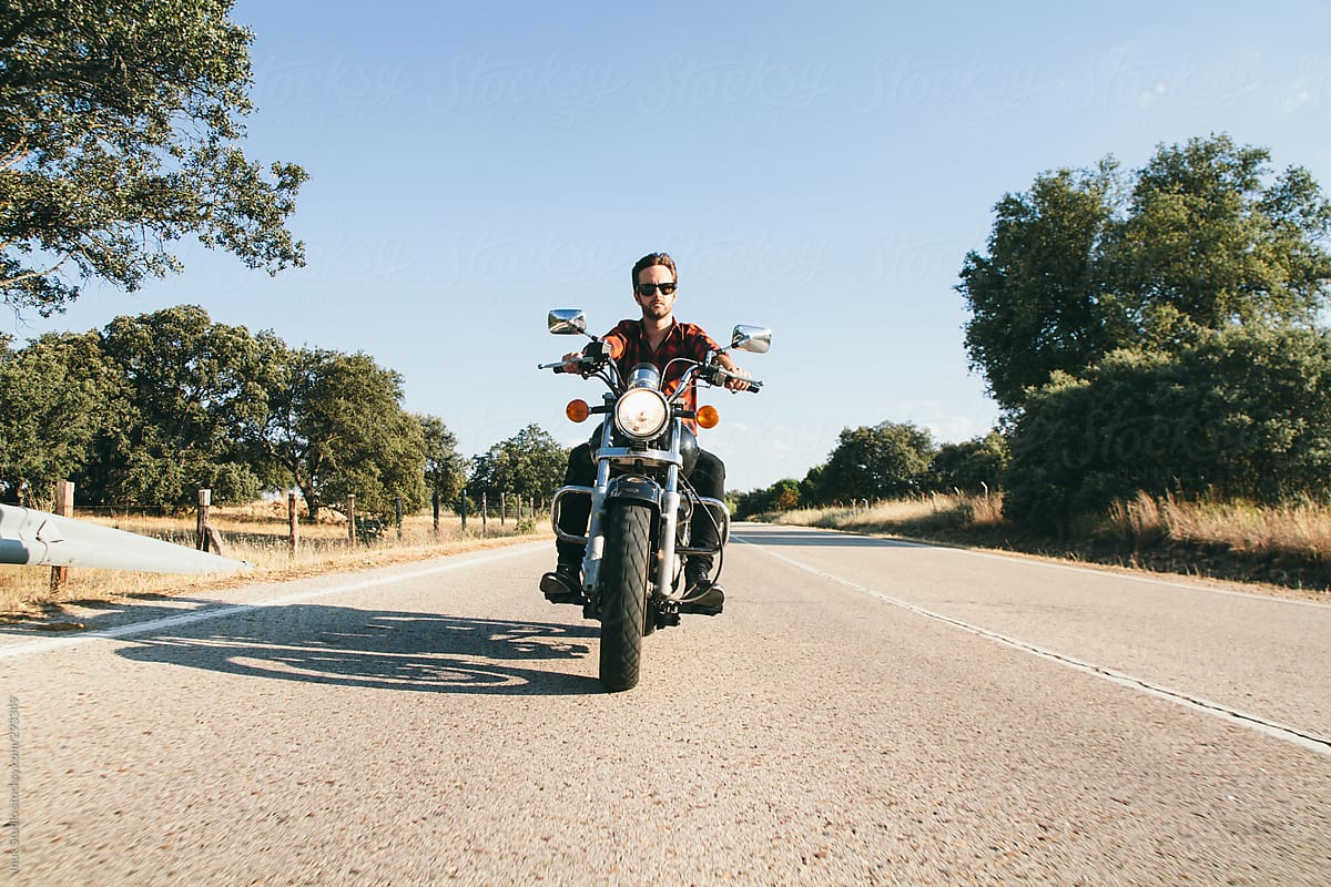 Man in shirt with sunglasses driving his motorbike on a road