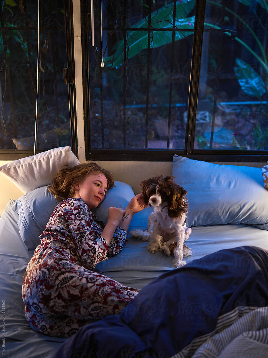Pleasant woman sleeping with dog on bed