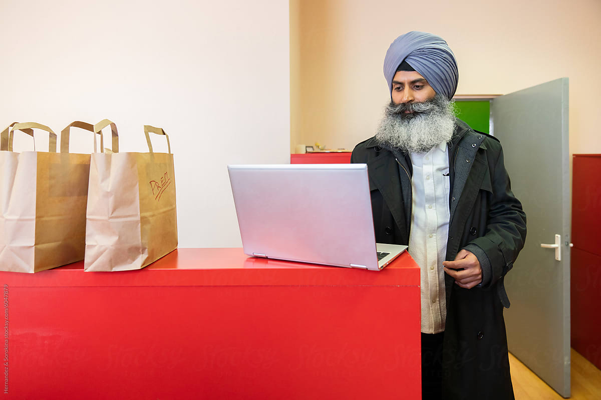 Indian Man Using Laptop At His Take Away Restaurant