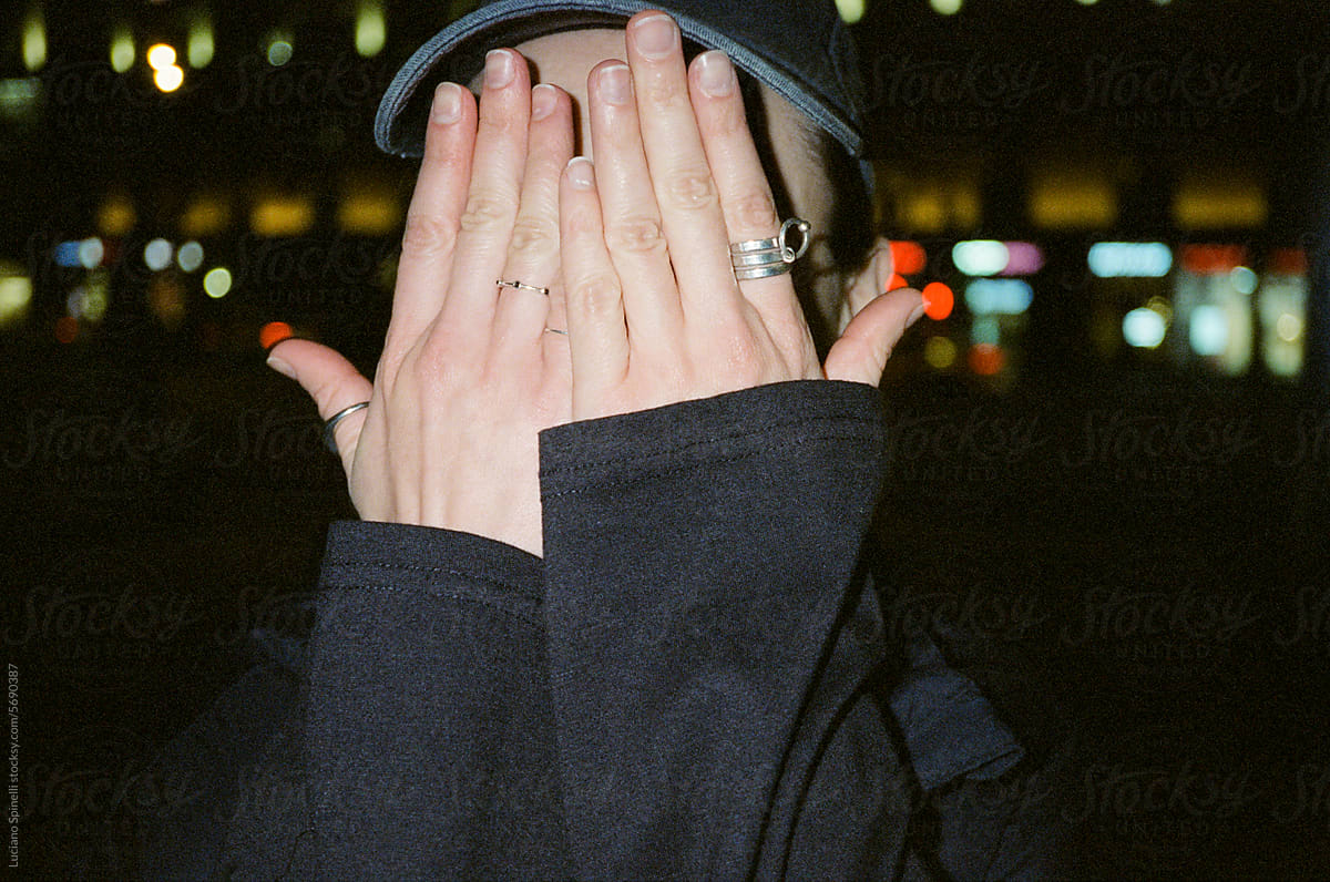 Anonymous woman covering her face with her hands wearing silver rings