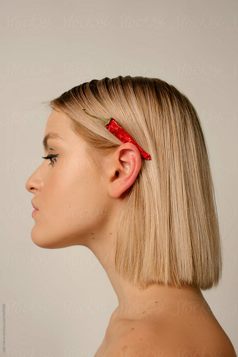 Profile View of Young blonde Woman With hot pepper