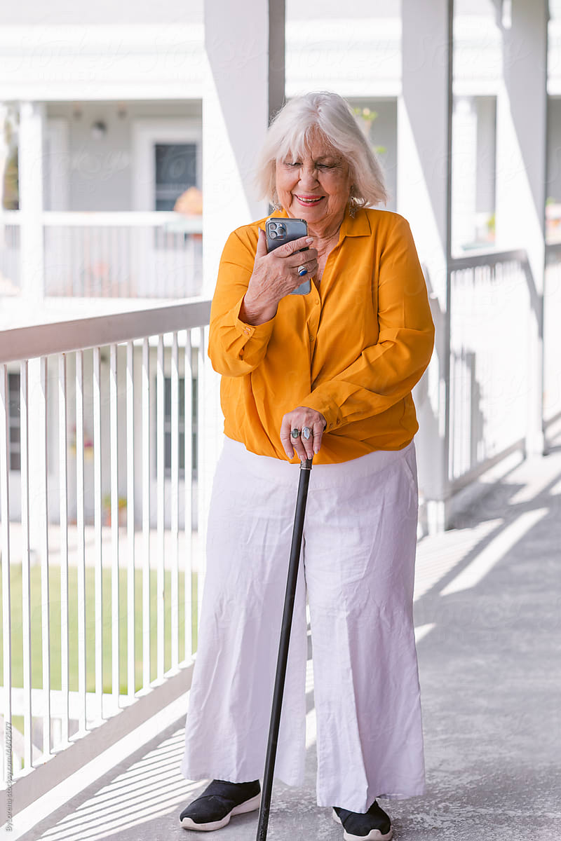 Elderly woman using smartphone outside residence