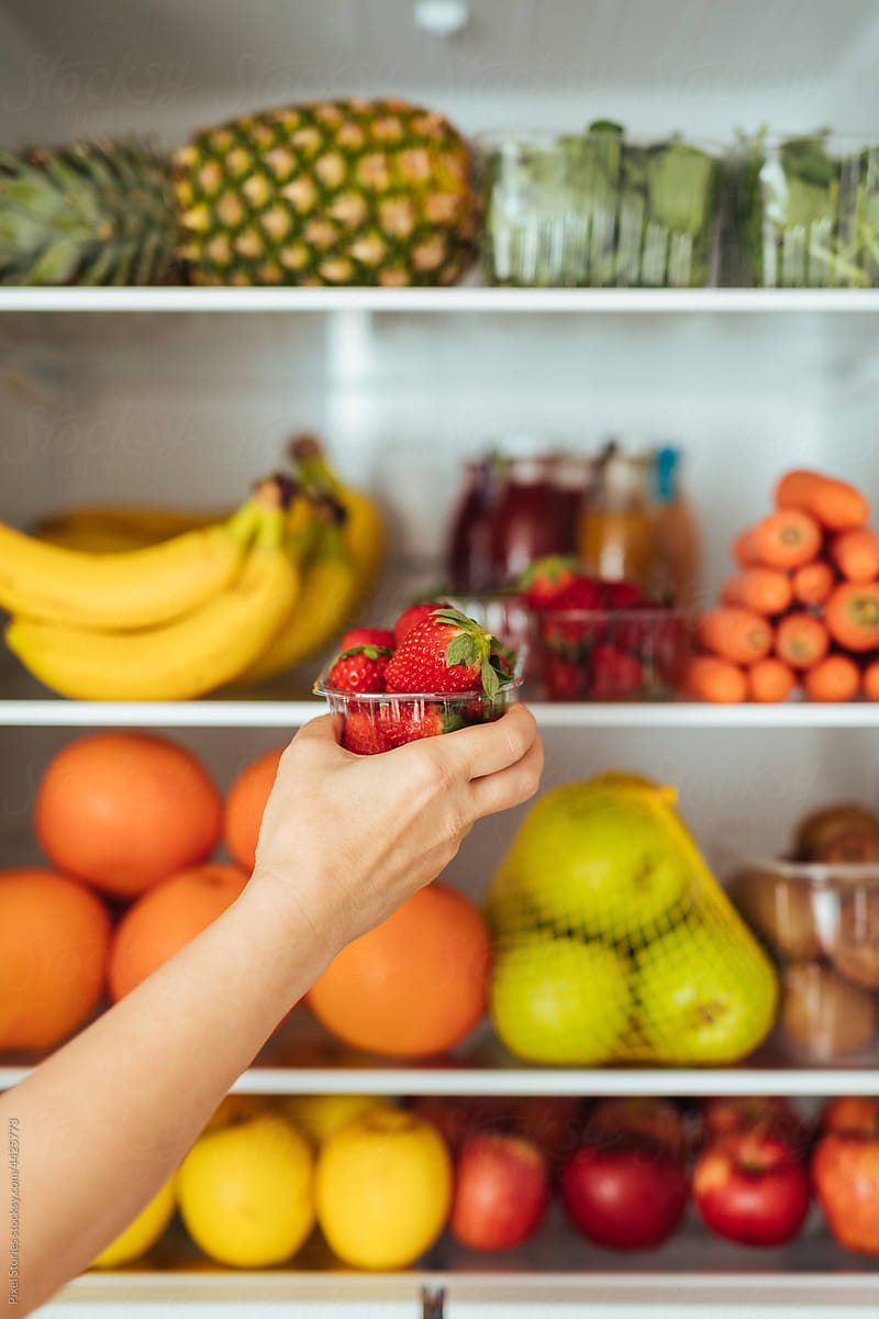 Healthy food concept: Grabbing strawberries from fridge