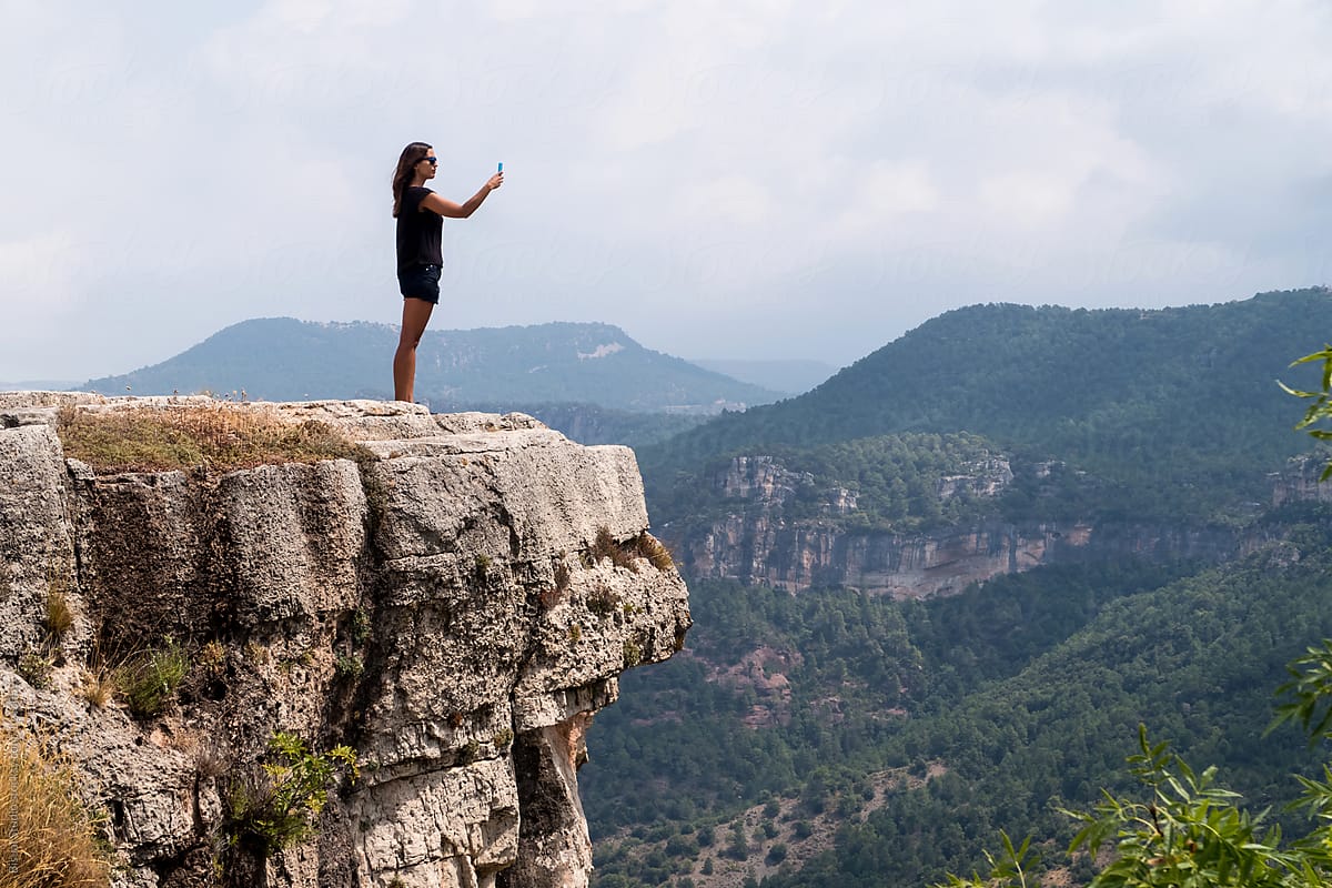 Woman on top of cliff against picturesque landscape
