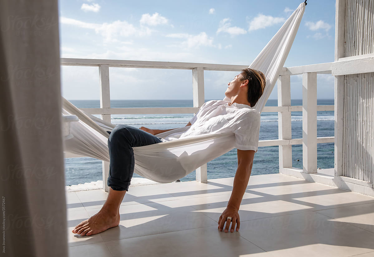 Young man sitting in the hammock overlooking the sea