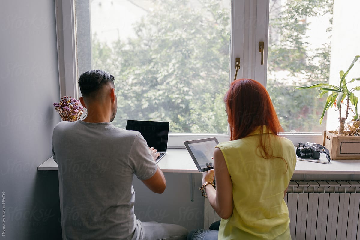 Anonymous Man and Woman Sitting by the Window Looking at their Computers